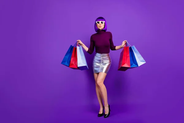 Фото красивої стильної леді, що тримає багато пакетів в руках, відправляє повітряний поцілунок носити модний наряд ізольований фіолетовий фон — стокове фото
