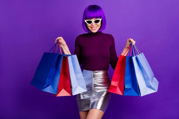 Incroyable dame élégante tenant des paquets dans les mains portent des spécifications de soleil tenue à la mode isolé fond violet — Photo