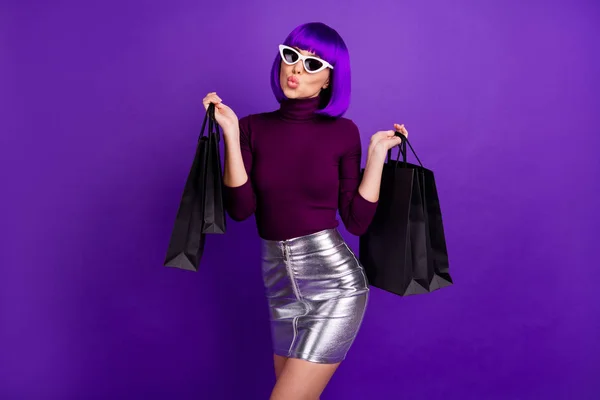 Mooie stijlvolle dame houden veel packs in handen verzenden Air Kiss dragen trendy outfit geïsoleerd paarse achtergrond — Stockfoto