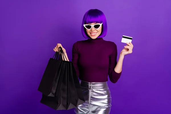 Retrato de consumidor encantador com óculos óculos segurando pacotes vestindo saia de prata gola alta isolado sobre fundo violeta roxo — Fotografia de Stock