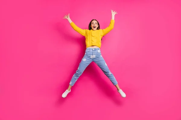 Foto de tamaño completo de linda dama con sus manos levantadas saltando usando suéter amarillo vaqueros punteados aislados sobre fondo fucsia — Foto de Stock