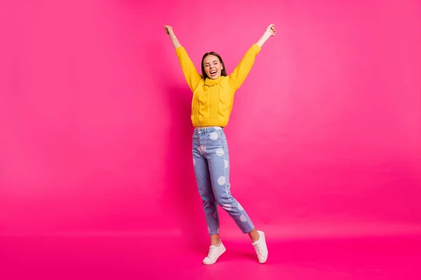 Full body foto di allegra signora alzando le braccia indossando pullover giallo punteggiato jeans denim isolato su sfondo fucsia — Foto Stock
