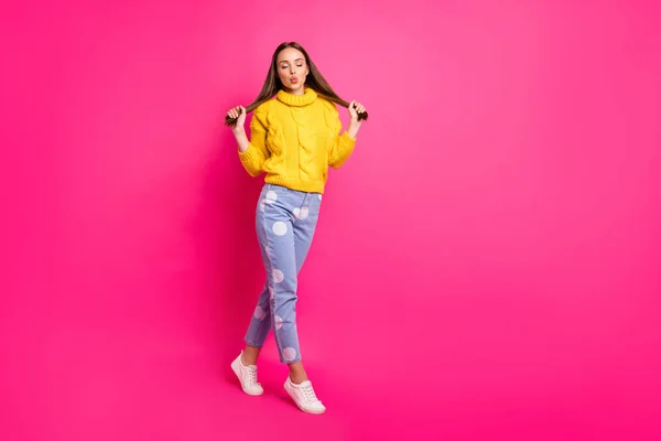 Fulll lengte foto van mooie dame aanraken haar kapsel met gesloten ogen verzenden van lucht kusjes dragen gele Pullover gestippelde denim jeans geïsoleerd over fuchsia achtergrond — Stockfoto