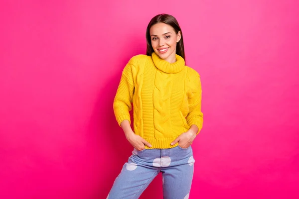 Retrato de menina linda olhando com sorriso radiante colocando as mãos em bolsos usando camisola de malha isolada sobre fundo fúcsia — Fotografia de Stock