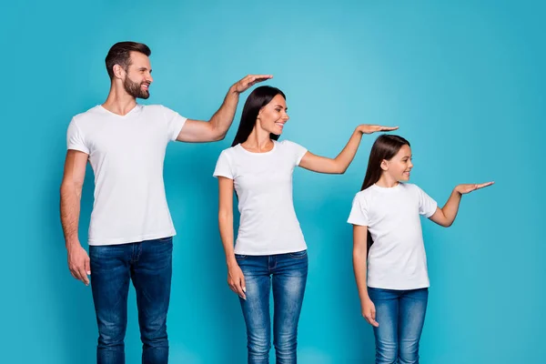 파란색 배경 위에 고립 된 흰색 티셔츠 데님 청바지를 입고 손을 잡고 브루넷 머리를 가진 달콤한 부모와 딸의 프로필 측면 사진 — 스톡 사진