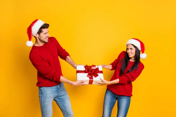Profile side of angry couple pull package wear red sweater pullover santa claus cap denim jeans isolated over yellow background — Stock fotografie