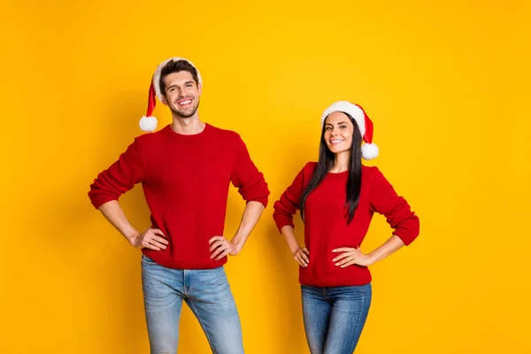 Retrato de cônjuges alegres em chapéus de Papai Noel olhar stand isolado sobre fundo amarelo — Fotografia de Stock
