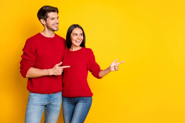 Perfil foto lateral de duas pessoas encantadoras apontar no espaço cópia mostrar promo desgaste camisola jeans jeans vermelho isolado sobre fundo amarelo — Fotografia de Stock