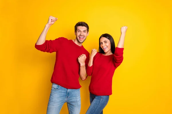 Retrato de homem e mulher alegre levantar seus punhos gritar sim celebrar vitória desgaste pulôver vermelho jeans jeans isolado sobre fundo amarelo — Fotografia de Stock