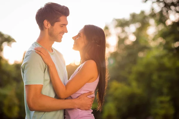 Foto del lado del perfil de la encantadora joven casada abrazándose usando colorida camiseta al aire libre — Foto de Stock