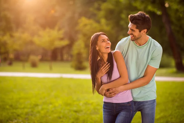Retrato de pareja alegre riendo disfrutando abrazando a cuestas usando camiseta vaqueros al aire libre —  Fotos de Stock