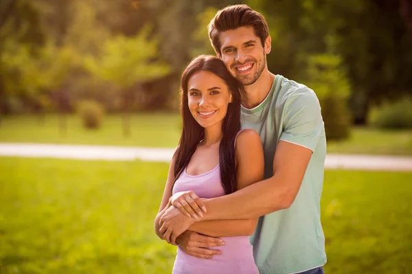 Portrait of charming sweethearts piggyback wearing bright t-shirt standing under sunset outdoors — Stock Fotó