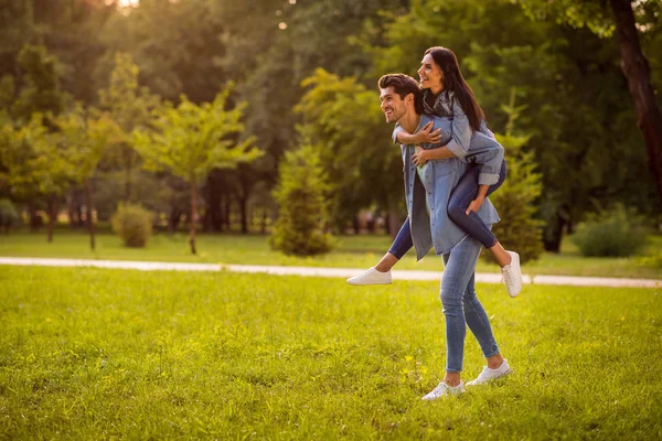 Full length profile side photo of lovely spouses piggyback wearing denim jeans jackets blazers outdoors — Stock Photo, Image
