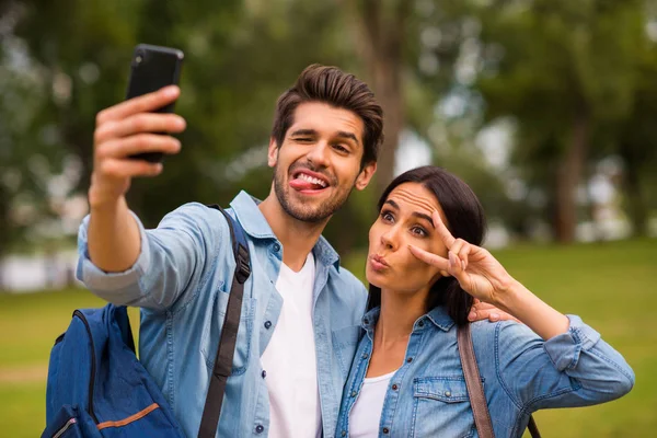 Zdjęcie beztrocznej pary nastroju przy użyciu telefonu robienia selfie z symbolem v-znak nosić casual denim strój — Zdjęcie stockowe