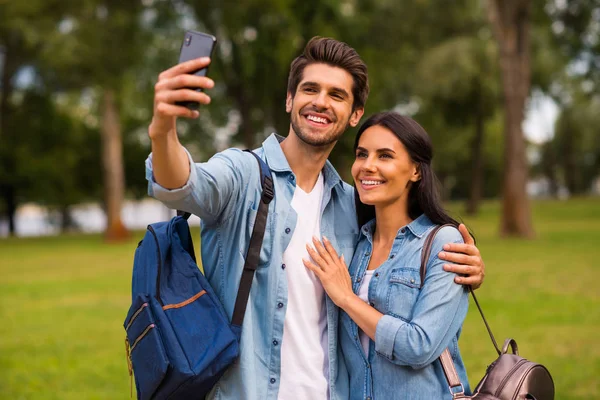 Zdjęcie tysiąclecia pary przy użyciu telefonu robienia selfie dzieje zielony park nosić casual denim strój — Zdjęcie stockowe
