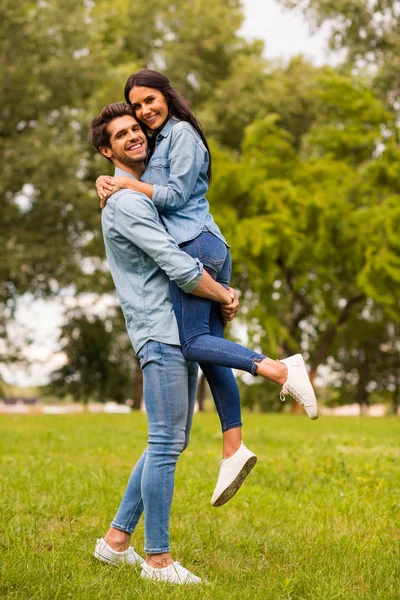 Фотография счастливой пары, проводящей лучшее время в джинсовой одежде в зеленом парке — стоковое фото