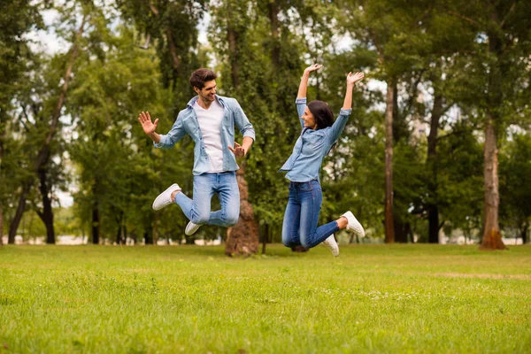 Full längd foto av överlycklig par hoppning hög i Green Park slitage denim outfit — Stockfoto