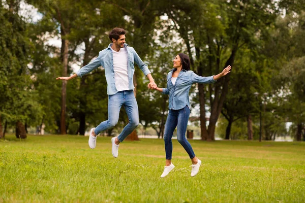 Foto de cuerpo completo de un lindo par de manos saltando alto en traje de mezclilla de desgaste verde parque —  Fotos de Stock