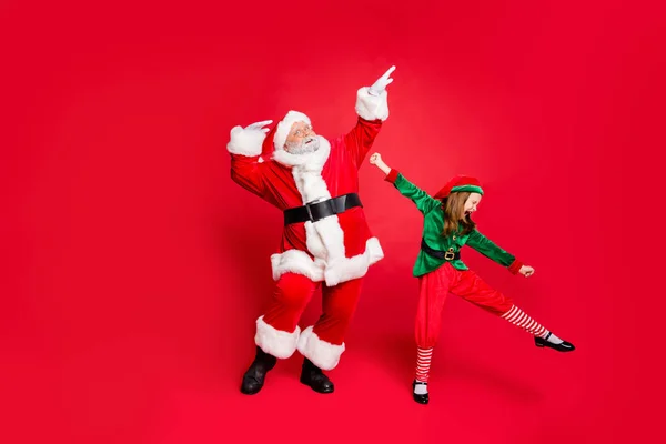 兴奋的圣诞老人和精灵在帽子与眼镜眼镜跳舞愚弄穿着明亮的服装孤立的红色背景的全尺寸照片 — 图库照片