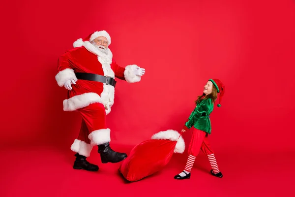 Full längd foto av Fairy Santa Claus Elf i hatt huvudbonader väska med nuvarande slitage gröna kostymer glasögon glasögon glasögon isolerade över röd bakgrund — Stockfoto