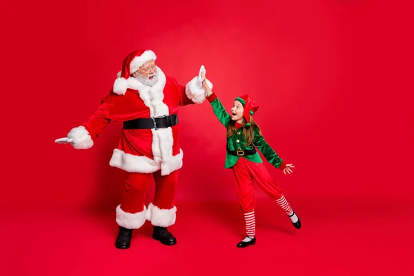 Full längd profilsida foto av upphetsad Santa Claus Elf fira framgång på Eve Noel preparationl klädd i grön kostym med hatt huvudbonader isolerade över röd bakgrund — Stockfoto