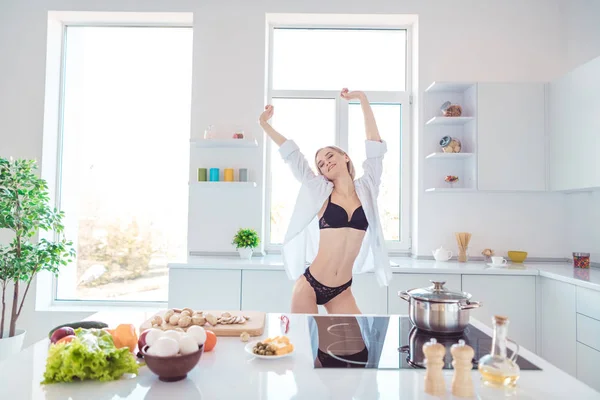 Retrato dela ela agradável-olhando atraente esportivo perfeito figura graciosa sonhador menina alongamento desfrutando dia devaneio cozinhar prato refeição na luz moderna branco interior cozinha hotel quarto — Fotografia de Stock