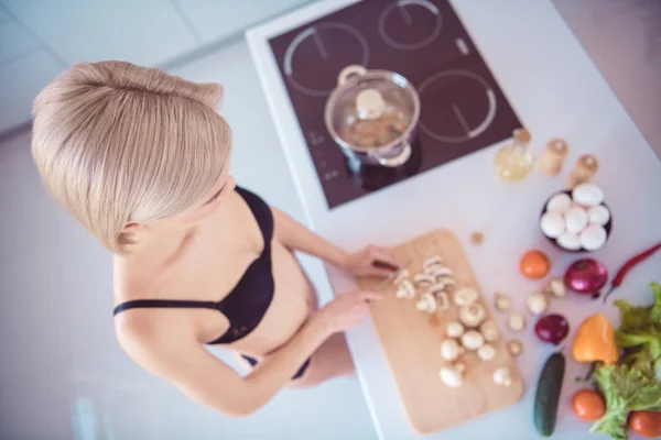 Фотографія красивої моделі приготування сніданку для хлопця, що ріже чемпіонство для салату в нижній білизні, бюстгальтер мереживні труси, що стоять на світлій кухні — стокове фото