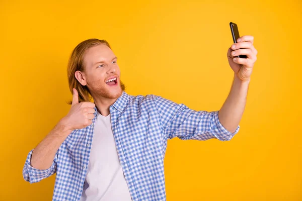 Foto di tendenza elegante redhair uomo eccitato mostrando pollice in su mentre blogging registrazione video scattare selfie con il telefono indossando camicia blu a scacchi isolato sfondo di colore vibrante — Foto Stock