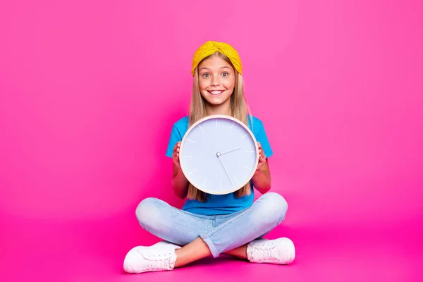 Volledige lengte foto van positieve vrolijke grappige funky Kid Hold klok voelen opgewonden wachten voor start dagelijkse routine slijtage Bright denim jeans sneakers geïsoleerd over glans kleur achtergrond — Stockfoto