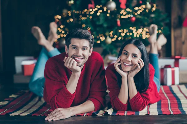 屋内でクリスマス休暇X-masの休日を楽しむイルミネーションと常緑モミの木の下に格子状の毛布の上に横たわっている2人のロマンチックなカップルのクローズアップ写真 — ストック写真