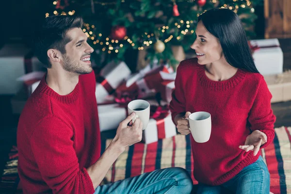 Foto von oben Winkel zwei romantische Menschen sitzen auf karierte Decke unter immergrünen Weihnachtsbaum mit Weihnachtsbeleuchtung halten Becher mit Heißgetränk sprechen genießen Neujahr Urlaub im Haus drinnen — Stockfoto