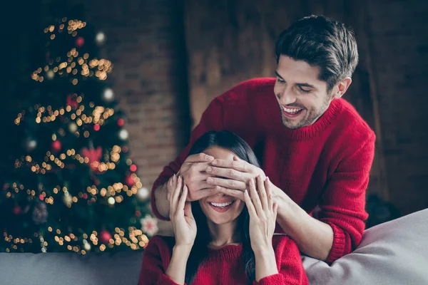 Retrato de dos personas alegre hombre cerrar sus ojos de mujer se sienten románticos en Navidad x-mas vacaciones de noche sentarse en diván en noel casa decorativa con luces de año nuevo en el interior —  Fotos de Stock