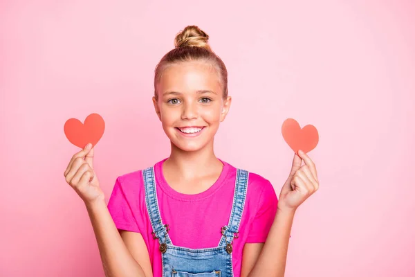 Foto de alegre bonito agradável estudante segurando duas formas de coração vermelho com as mãos vestindo fuchsia t-shirt isolado sobre fundo cor pastel — Fotografia de Stock