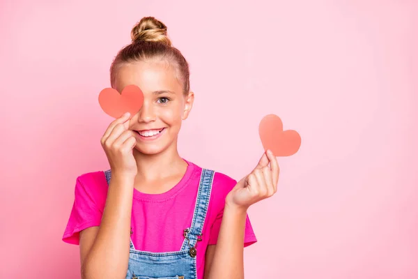Copyspace fotka roztomilé veselé dívky, která se dívá z červeného srdce a s zubím se usmívá, nosí fučsie a košile džíny, izolované přes růžové pastelové barevné pozadí — Stock fotografie