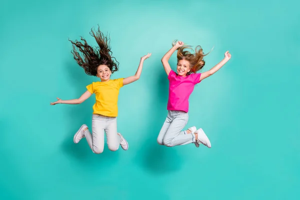 Longitud completa tamaño del cuerpo foto de dos saltando regocijo personas alegres chicas divirtiéndose juntos mientras se aíslan con fondo verde azulado —  Fotos de Stock