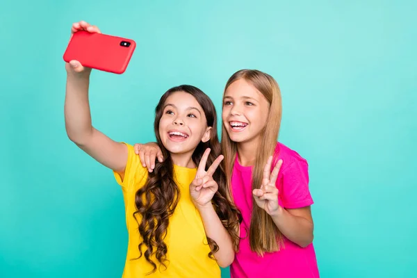 Fotó két izgatott aranyos jó trendi gyönyörű szőke barna lány viseli az emberek t-shirt sárga rózsaszín kiadások szabad idő, amely megmutatja, v-jel felvétel videó, míg elszigetelt réce háttér — Stock Fotó