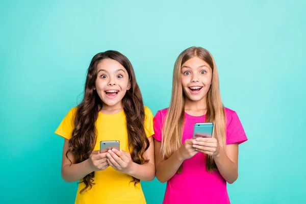 Foto de dos moda disfrutando feliz loco animó a la gente con camisetas de color rosa amarillo ver algo irreal en la pantalla, mientras que aislado con fondo turquesa —  Fotos de Stock