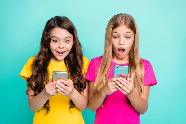 Photo de deux sœurs regardant les ventes commencer sur leur téléphone alors qu'elles sont isolées avec fond de sarcelle — Photo