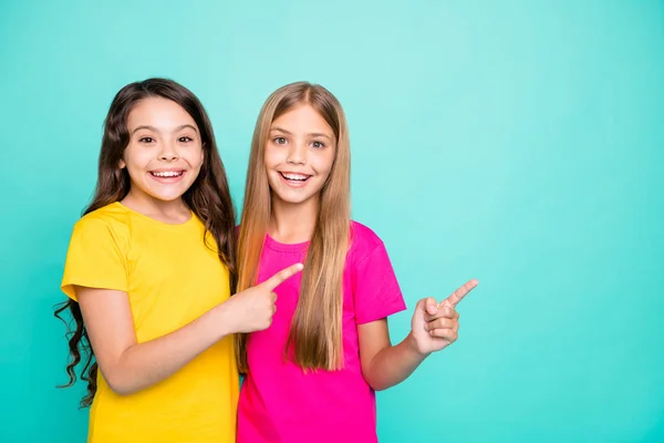 Foto av två casual fina söta flickor pekar på plats där kan vara något som anges medan isolerade med kricka bakgrund — Stockfoto