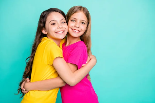 Фото двух милых удивительных девушек с длинными волосами, обнимающих друг друга в изоляции с бирюзовым фоном — стоковое фото