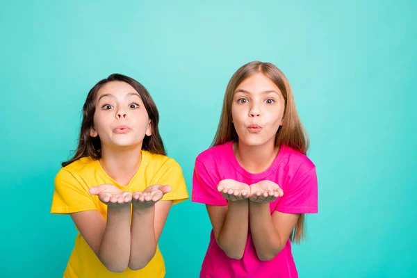 Foto di due giocherelloni amichevoli ragazze gentili che indossano colorate t-shirt rosa e gialle mentre isolato con sfondo verde acqua — Foto Stock