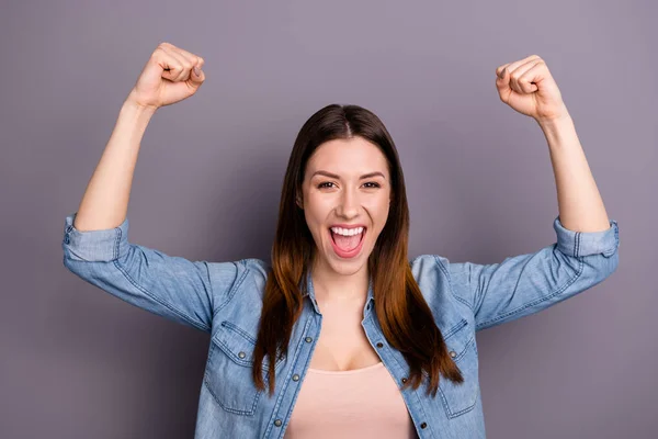 Porträtt av galen glad kvinna höjer knytnävarna ropa Ja fira seger slitage denim jeans outfit isolerade över grå färg bakgrund — Stockfoto