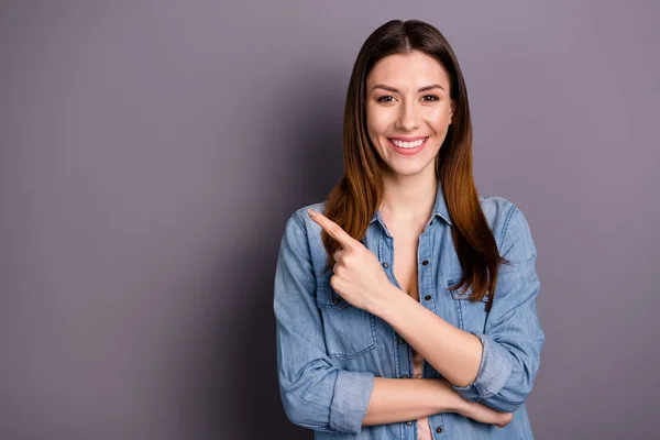 Retrato de bem sucedido positivo senhora indicador de ponto dedo no espaço de cópia recomendo anúncios descontos desgaste jeans roupas isoladas sobre fundo de cor cinza — Fotografia de Stock