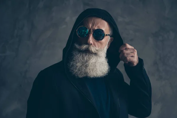 Retrato de cerca de su agradable bien vestido atractivo concentrado contenido barbudo hombre de pelo gris con capucha ronda especificaciones vida estilo de vida aislado sobre fondo de pared industrial de hormigón — Foto de Stock