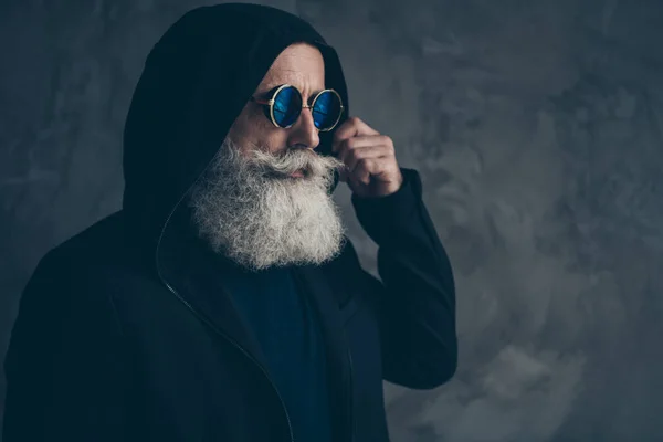 Gros plan profil vue de côté portrait de beau contenu attrayant bien habillé barbu homme aux cheveux gris grand-père portant mettre sur capuche ronde spécifications isolé sur fond de mur industriel en béton — Photo