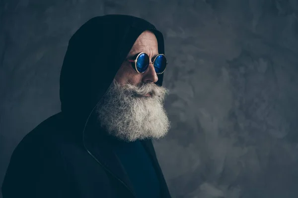 Perfil de cerca retrato lateral de su agradable contenido enfocado atractivo barbudo hombre de pelo gris abuelo con sudadera con capucha ronda especificaciones vida estilo de vida aislado sobre fondo de pared industrial de hormigón — Foto de Stock