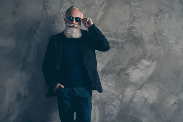 Portrait d'un homme masculin sévère chic touchant ses spécifications en portant un pantalon veste noire isolé sur fond gris — Photo