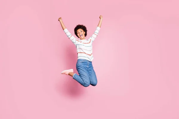 Ganzkörpergröße Foto von fröhlich niedlich charmant positive süße hübsche schwarze Millennial springen mit Glück tragen Jeans Jeans weiß gestreiften Pullover isoliert rosa pastellfarbenen Hintergrund — Stockfoto