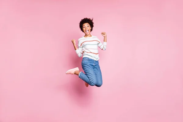 Full längd kroppsstorlek foto av extatisk överlycklig glädje Svart flicka skrikande hoppar upp bär Jeans denim randig vit tröja isolerad över pastell rosa färg bakgrund — Stockfoto