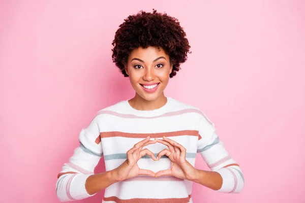 Photo of cute nice charming attractive girl wearing white striped sweater smiling cheerfully toothily showing you heart shape sign isolated pink pastel color background